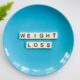 Weight loss on a blue plate spelt with scrabble letters