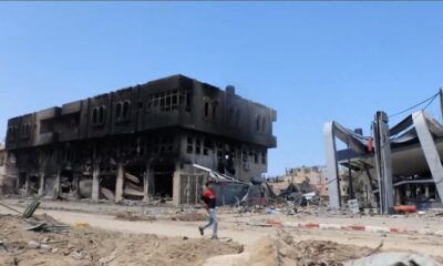 A person walks past destroyed buildings in Khan Younis