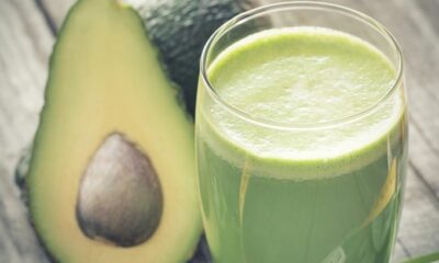 Creamy Avocado Pear Smoothie in tall glass next to avocado cut in half