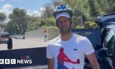 Djokovic greets fans with a helmet after being hit by bottle