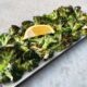 Air Fryer Roasted Garlic Parmesan Broccoli in serving dish with lemon wedge.