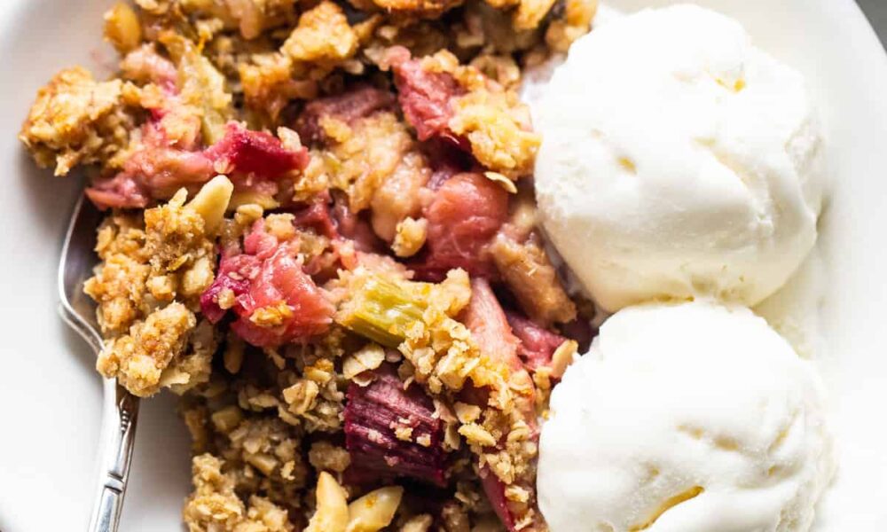 A bowl of rhubarb crisp with ice cream and granola.