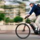 Man in casual business attire and bike helmet rides electric bike