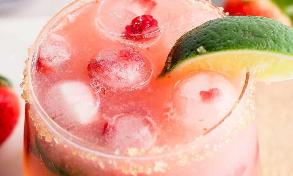 A refreshing strawberry cocktail with ice, lime, and a sugared rim.