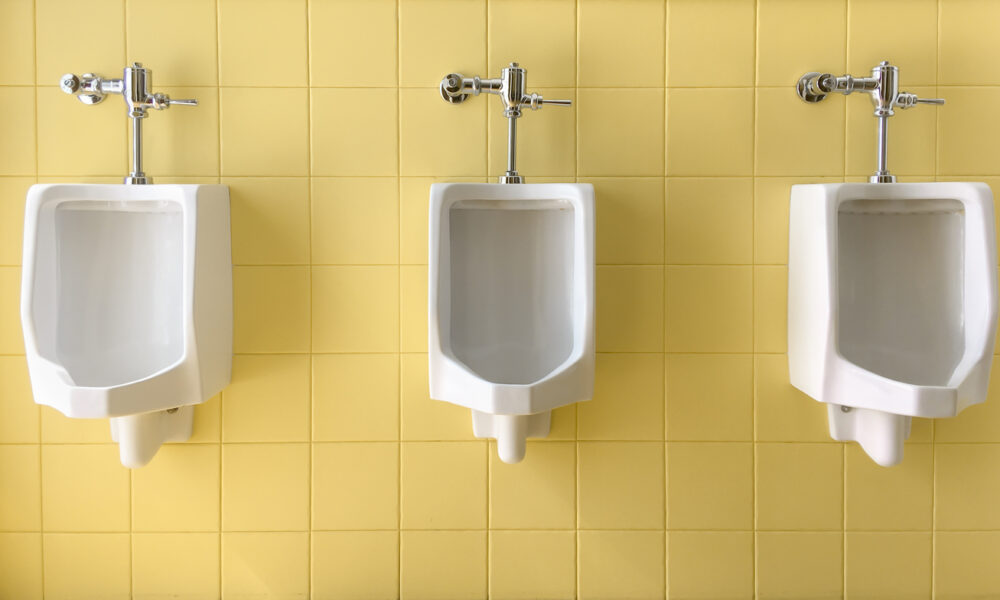 Urinal in front of yellow tiled wall