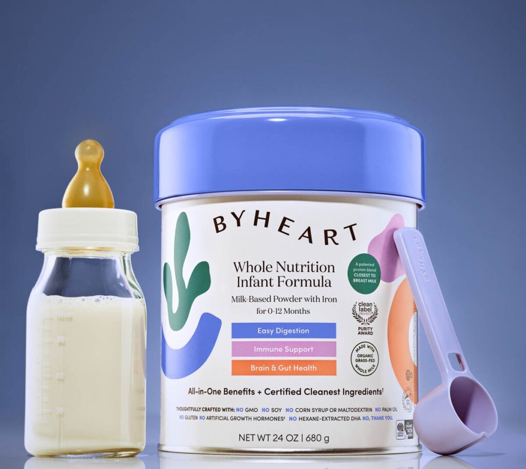 ByHeart infant formula can on a blue background with a bottle and scoop next to it.