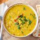 Slow cooker dal served in a white bowl, garnished with cilantro, with naan on the side.