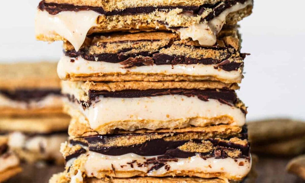 A stack of s'mores with melted marshmallows and chocolate between graham crackers, set against a wooden backdrop.