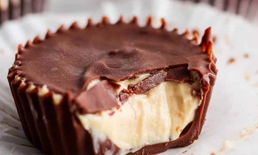 A close-up of a peanut butter cup with a bite taken out, revealing creamy peanut butter filling and a thick chocolate shell.