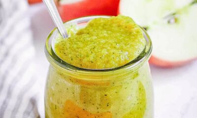 Zucchini baby food puree in a glass jar with a spoon.