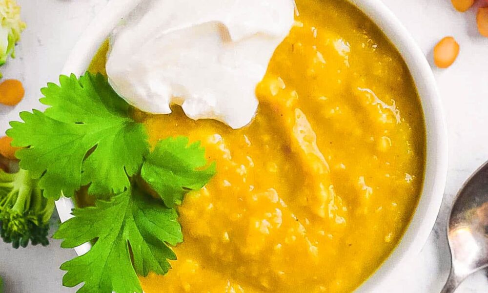 Lentils for baby served in a white bowl with some fresh herbs and veggies on the side.