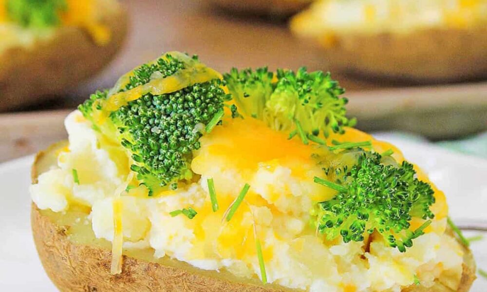 Healthy baked potato topped with broccoli and cheese, served on a white plate.