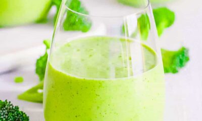 Healthy broccoli smoothie with banana in a glass on a white countertop.