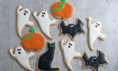 Whole wheat Halloween cookies in shapes of ghosts, cats, bats, and pumpkins sit on a gray counter.